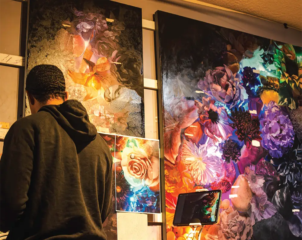 Noé Barnett working among colorful floral artwork in his studio