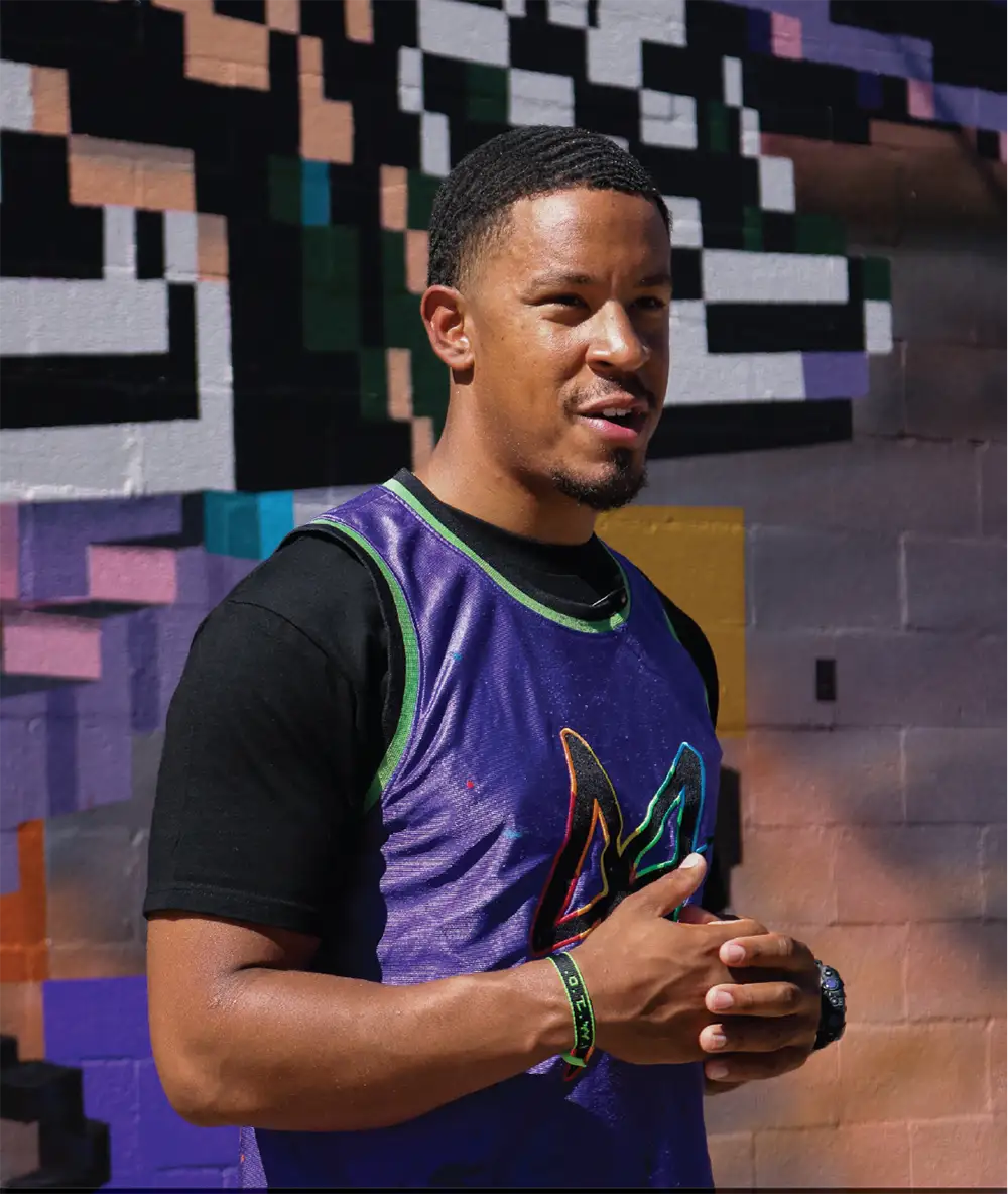 Noé Barnett speaking in front of the Mother Moment mural